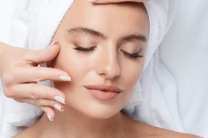 Perfect  girl with thick eyebrows and perfect skin at white background, towel on head, beauty photo concept, skin care, spa concept, facial massage, relax.